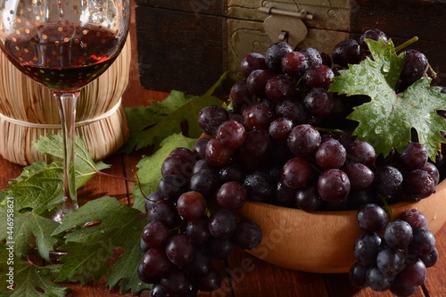 Fresh Black Grapes in Wooden bowl on Wooden Table with red wine