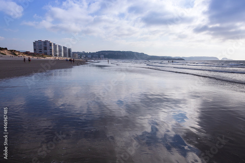 Playa de Salinas al anochecer y marea baja con reflejos de las nubes sobre la arena mojada