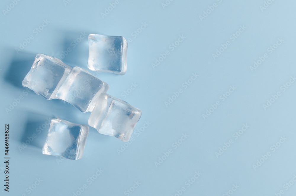 Transparent chilled artificial ice cubes on a light blue background. Background of transparent ice cubes and a blue background top view. Transparent chilled artificial ice cubes on a light blue background. Background of transparent ice cubes and a blue background top view.