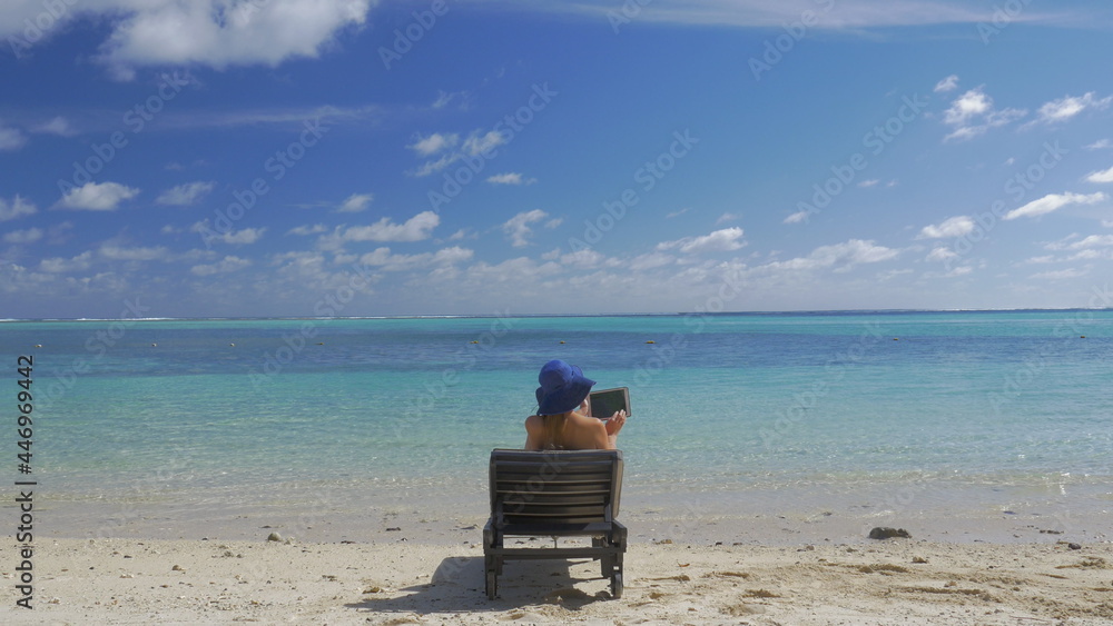 Tropical resort and woman sunbathing with tablet computer