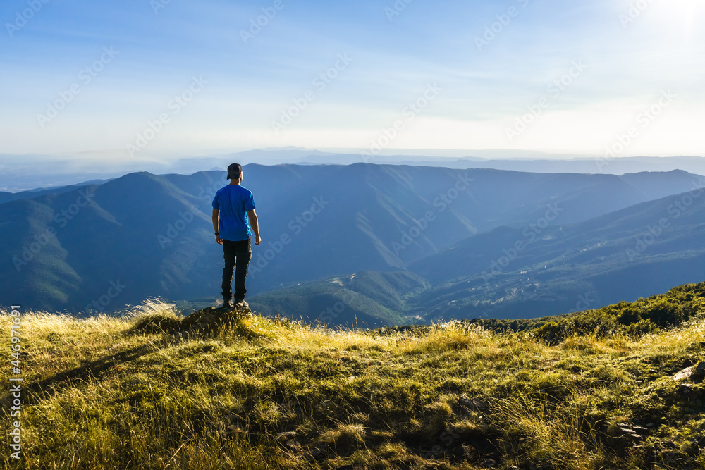 unrecognizable adventurous man looking at the horizon on top of a mountain on a summer's day