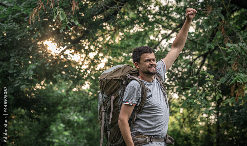 A man with a large backpack on a hike in the forest.