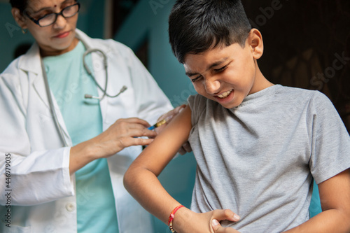 Young Indian boy receiving an injection by female doctors and shouting.  
