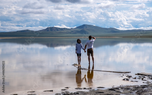 a guy and a girl on the shore of a high mountain lake
