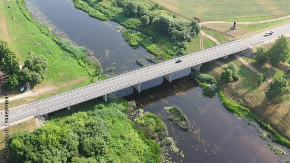 Aerial orbiting view of cars driving over bridge. River flowing under bridge Aerial orbiting view of cars driving over bridge. River flowing under bridge