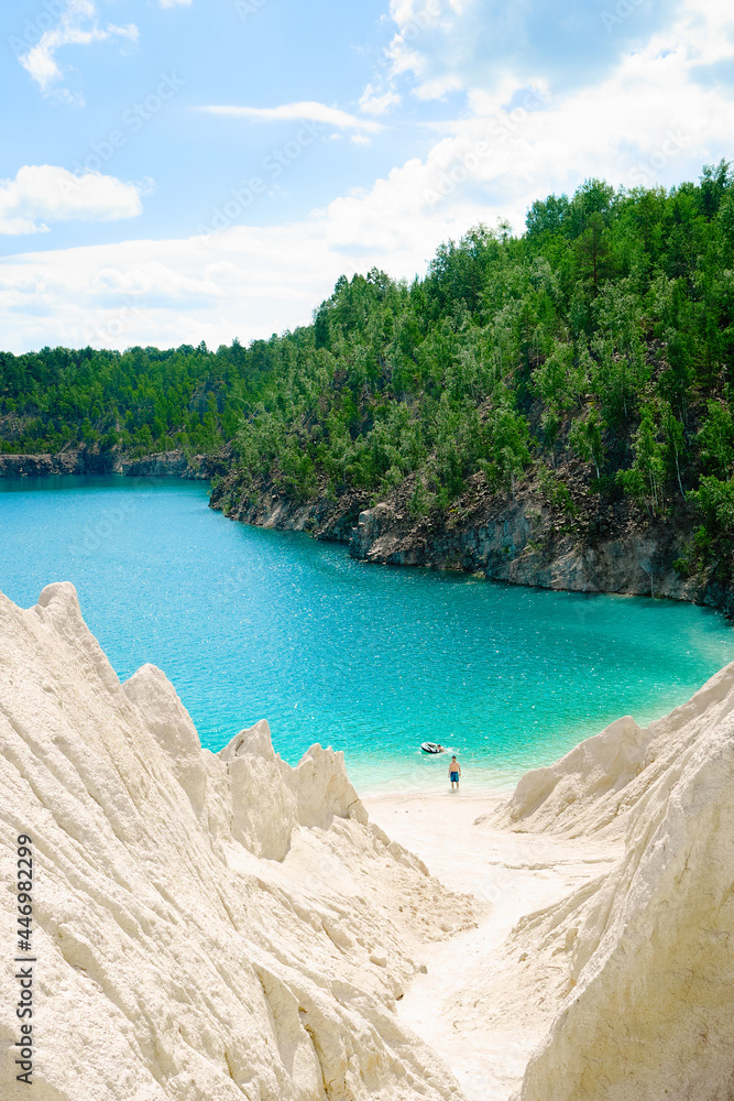 Beach with sandy rocks on a blue lake. Summer vacation, hot sun