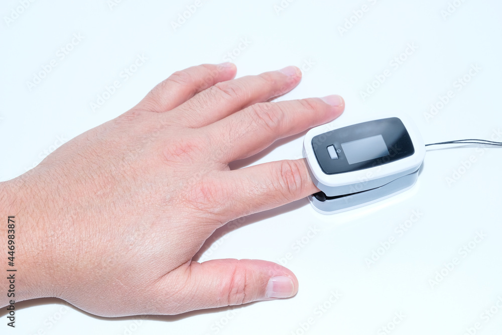 Pulse oximeter on the index finger on a white background. Measurement of blood oxygen and pulse. View from above. Lung disease. Concept Pulse oximeter on the index finger on a white background. Measurement of blood oxygen and pulse. View from above. Lung disease. Concept