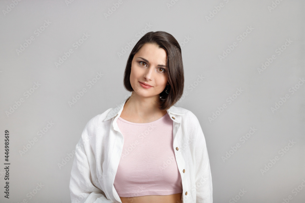 High key calm portrait of young brunette mixed race woman in pink tank and white shirt looking at camera High key calm portrait of young brunette mixed race woman in pink tank and white shirt looking at camera