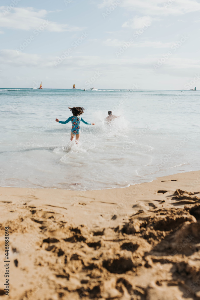 Father and daughter run into ocean on beach in Waikiki Father and daughter run into ocean on beach in Waikiki