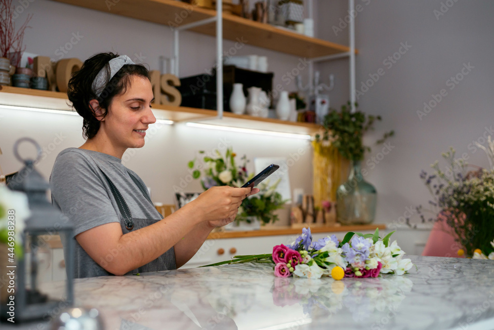 Young florist taking photo of flowers in her studio Young florist taking photo of flowers in her studio