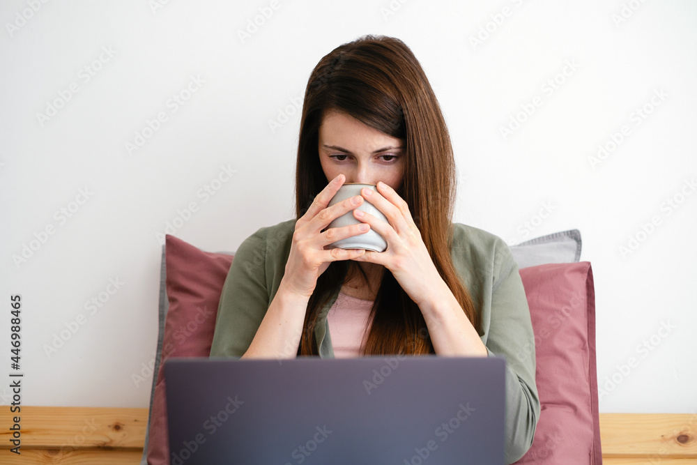 Young woman watching video by laptop and drinking coffee. Young woman watching video by laptop and drinking coffee.