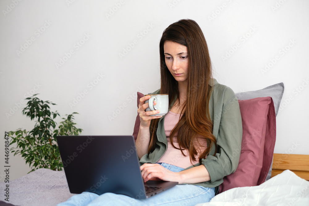 Young woman relaxing at home, using laptop and drinking coffee. Young woman relaxing at home, using laptop and drinking coffee.