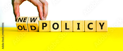 New or old policy symbol. Businessman turns wooden cubes and changes words 'old policy' to 'new policy'. Beautiful yellow table, white background. Business, old or new policy concept. Copy space.