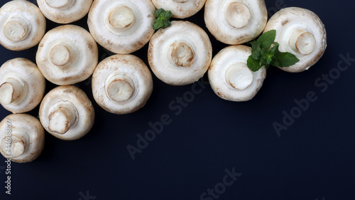 Champignon mushrooms and mint leaves on a dark background