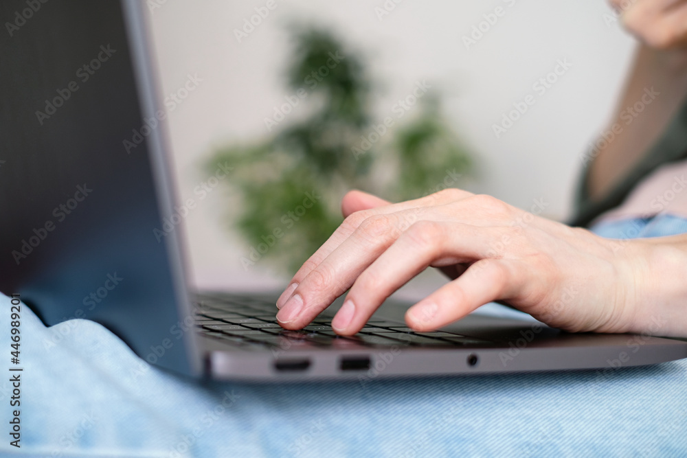 © Cavan - Close-up woman's fingers typing on a laptop.