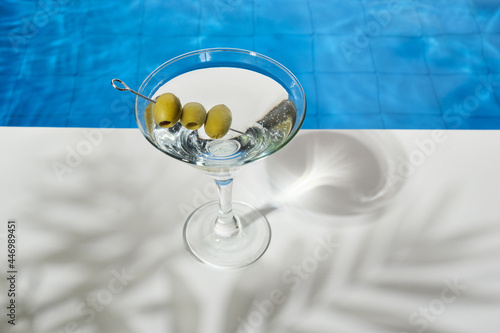 Cocktail glass with martini and olives by the pool. Soft drinks on a hot summer day day. Beach party in summer