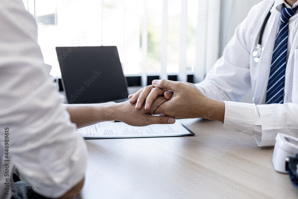 The doctor shakes hands to encourage the patient after the diagnosis results are finished, the patient detected a serious disease in the early stages. Concept of disease diagnosis.