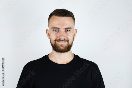 Portrait of a young man with a short beard on a light background, he is smiling, he is in a good mood, the guy waited a long time until the beard grows