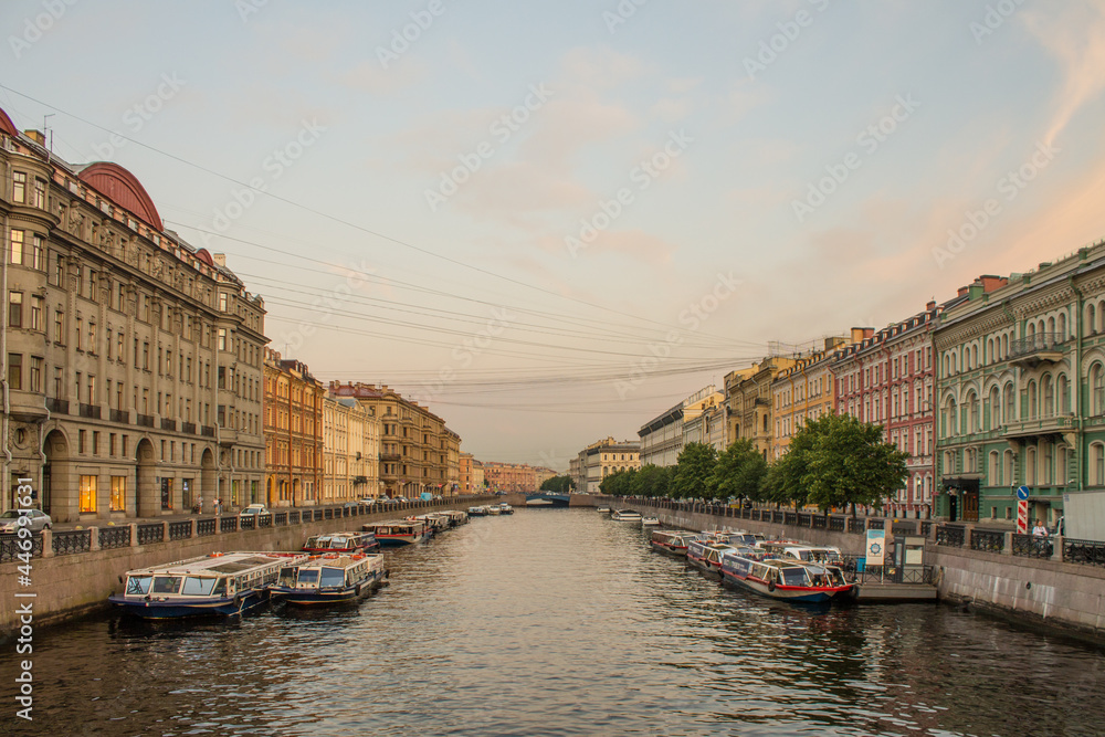 Saint PETERSBURG, RUSSIA-July, 15, 2021: Moika River embankment with moored boats with reflections in the water and historical buildings in the early summer morning