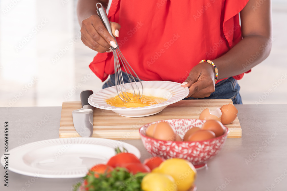 Close up of afro american woman using a whisk on some eggs: Cooking concept