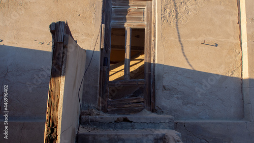 Sandfilled room viewed through a broken wooden door at Kolmanskop, ghost town, of Namibia. photo