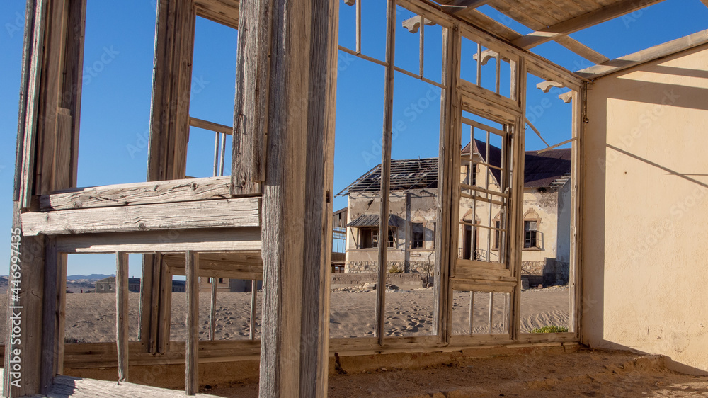View through a wooden window frame of one of the neglected houses at the ghost town of Kolmanskop.