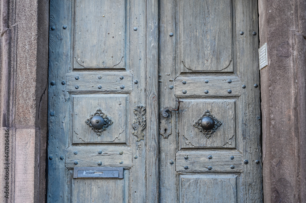 An antique wooden door with metal door handles.