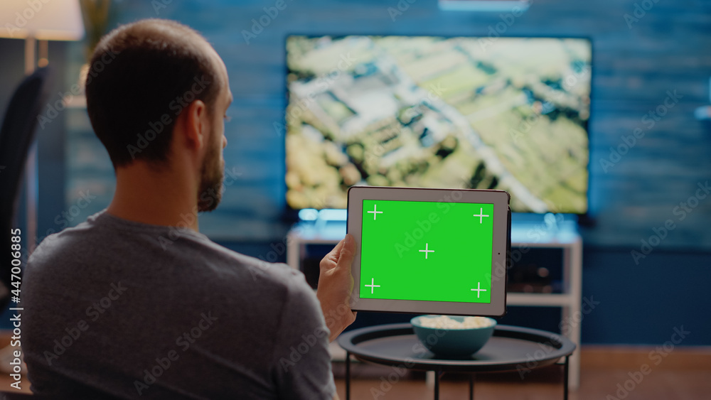 Person using modern tablet horizontally for green screen display in living room at home. User of chroma key for mockup template design and isolated background on copy space device Person using modern tablet horizontally for green screen display in living room at home. User of chroma key for mockup template design and isolated background on copy space device
