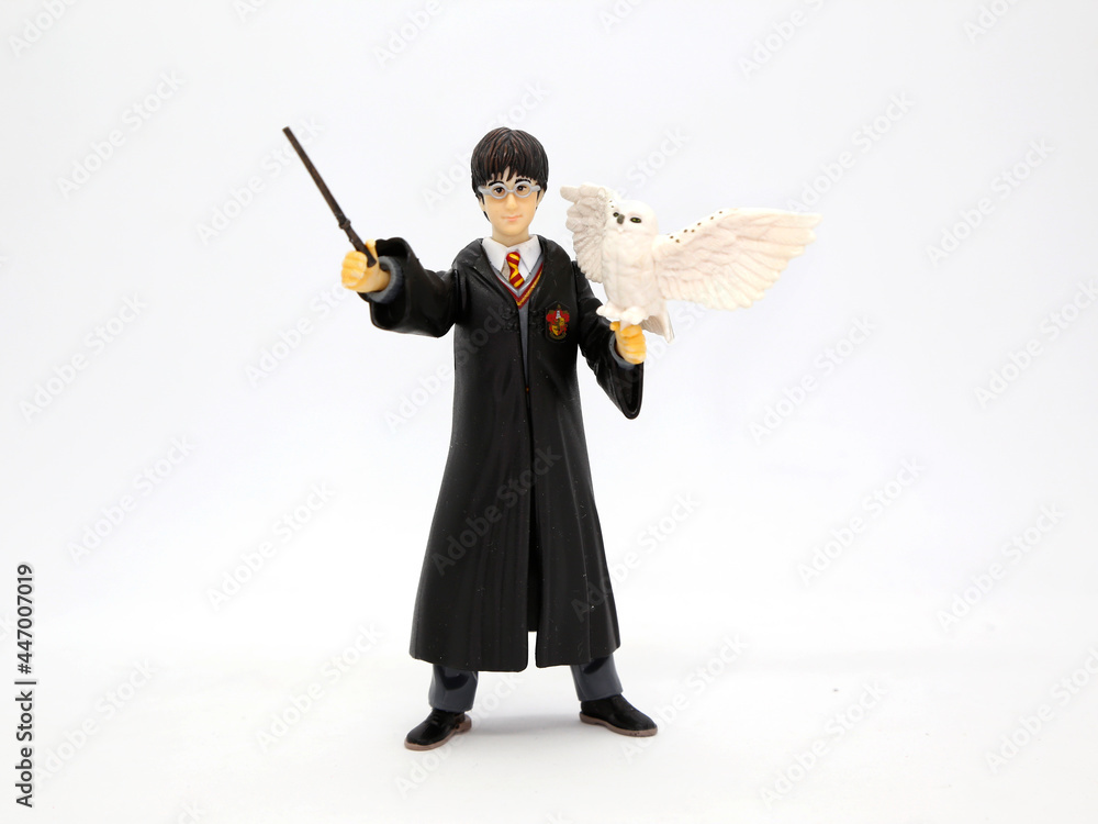 Naklejka premium Harry Potter with his white owl Hedwig. Harry dressed in his Hogwarts School of Witchcraft and Wizardry uniform and his wand in hand. Collectible toy for children. Character from the J. K. Rowling.