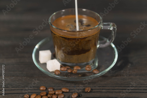 Zalewanie zaparzonej czarnej kawy mlekiem.