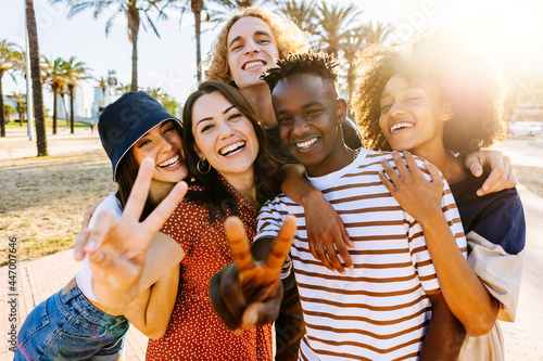 Portrait group of young multicultural trendy friends looking at camera while standing by palm trees background - Outdoor photo of diverse happy people having fun in summer - Focus on black guy photo
