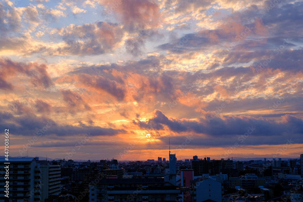 Fototapeta premium 兵庫県神戸市東灘区のマンション高層階から撮影した日の出。梅雨明け後、まだ雲が残るが、オレンジ色に染まりドラマチックな都会の朝。
