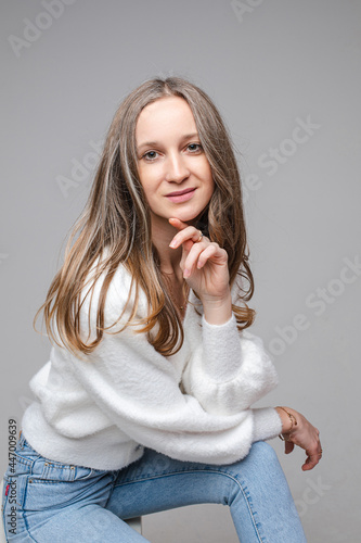 Smiling beautiful woman in a white sweater posing in studio
