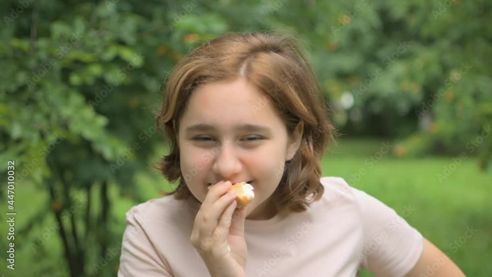 Portrait of a teenage girl eating ice cream. A girl eats delicious ice cream outdoors. A sunny summer day.Frames in 4K format Portrait of a teenage girl eating ice cream. A girl eats delicious ice cream outdoors. A sunny summer day.Frames in 4K format