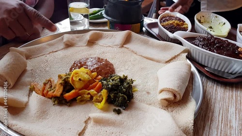 Serving an injera meal, with shiro, lentils, egg and a variety of vegetables photo