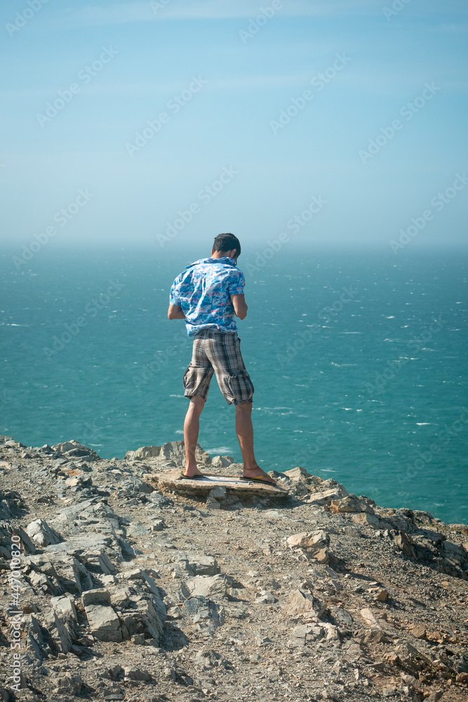 Young Latin Man on the Precipice of a Mountain Overlooking the Sea in the Desert in Uribia, La Guajira, Colombia