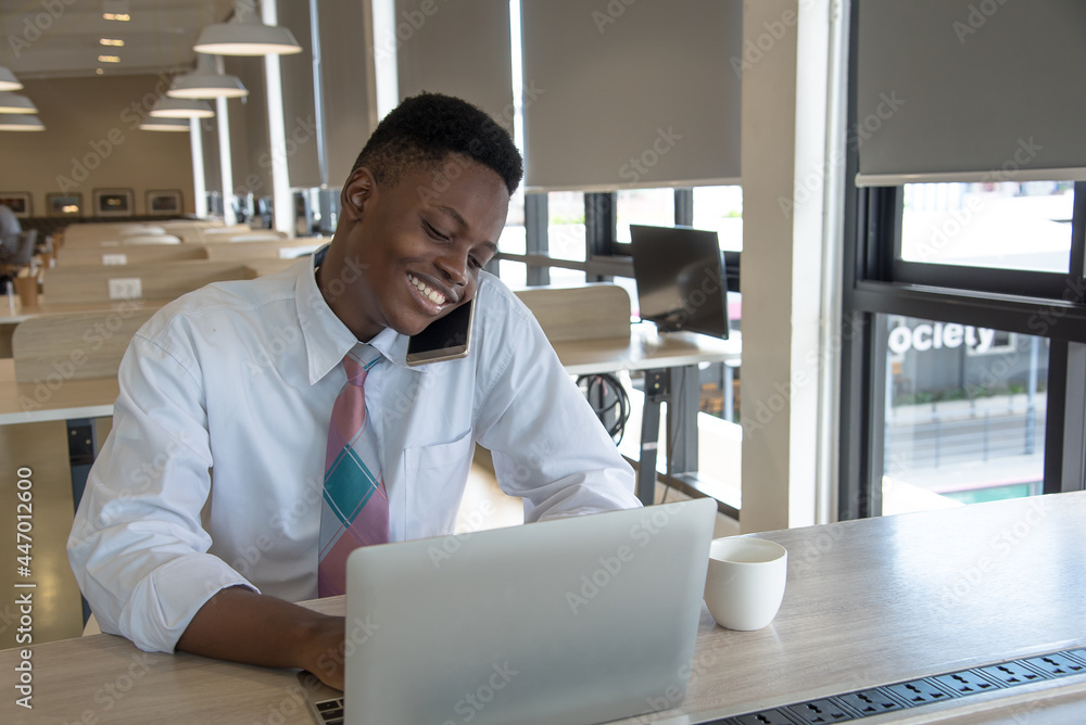Naklejka premium african guy use mobile and notebook smile and happy
