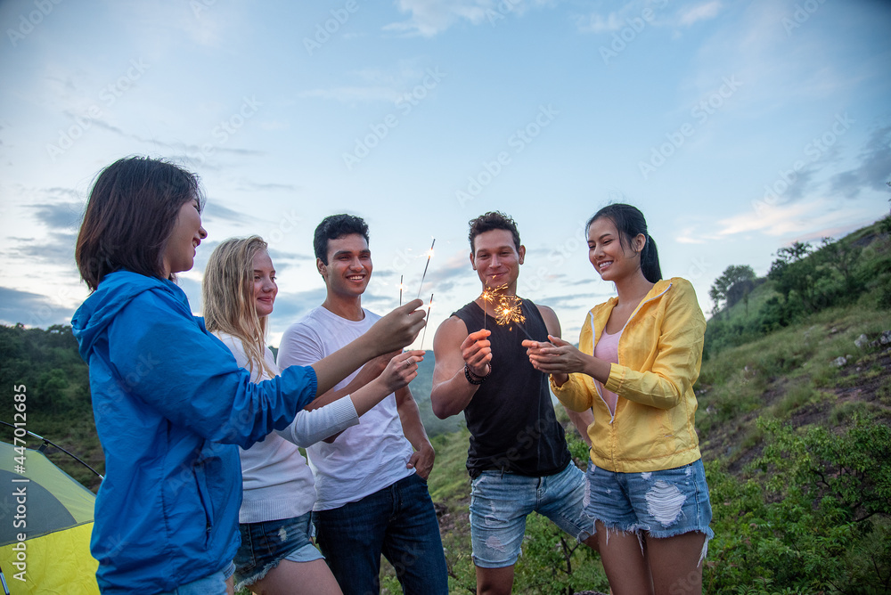 Group of Friends happily playing sparklers, background is beautiful mountain view Group of Friends happily playing sparklers, background is beautiful mountain view