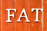 Alphabet letter in word FAT (Obesity or abbreviation of factory acceptance test, file allocation table) on old red color wood plate background