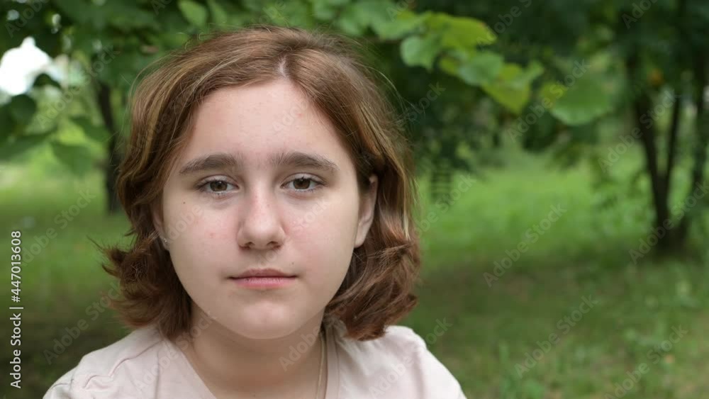 Portrait of a teenage girl Looking into a camera Standing on the street in a park on a Summer day. A Young Sad Thinking Curious Child Looks at the camera Close-up in the open air. The Face Is The Eyes Portrait of a teenage girl Looking into a camera Standing on the street in a park on a Summer day. A Young Sad Thinking Curious Child Looks at the camera Close-up in the open air. The Face Is The Eyes