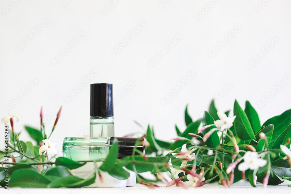 Green ombre essential oil roll on bottles surrounded by 1ml amber sample drams and delicate jasmine flowers Green ombre essential oil roll on bottles surrounded by 1ml amber sample drams and delicate jasmine flowers