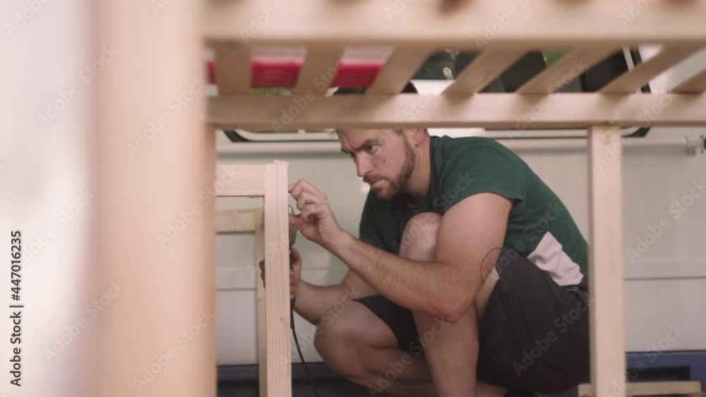 Man with beard working on wood construction interior inside self made van camper for holiday trips,close up Man with beard working on wood construction interior inside self made van camper for holiday trips,close up