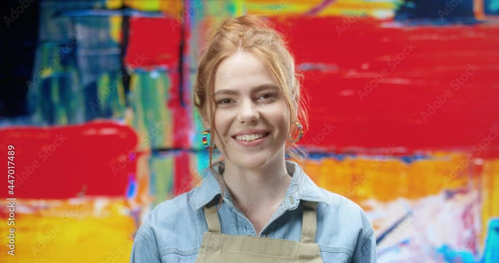 Portrait of a beautiful red-haired creative woman in denim shirt and apron and looking at camera smiling. Portrait of a beautiful red-haired creative woman in denim shirt and apron and looking at camera smiling.