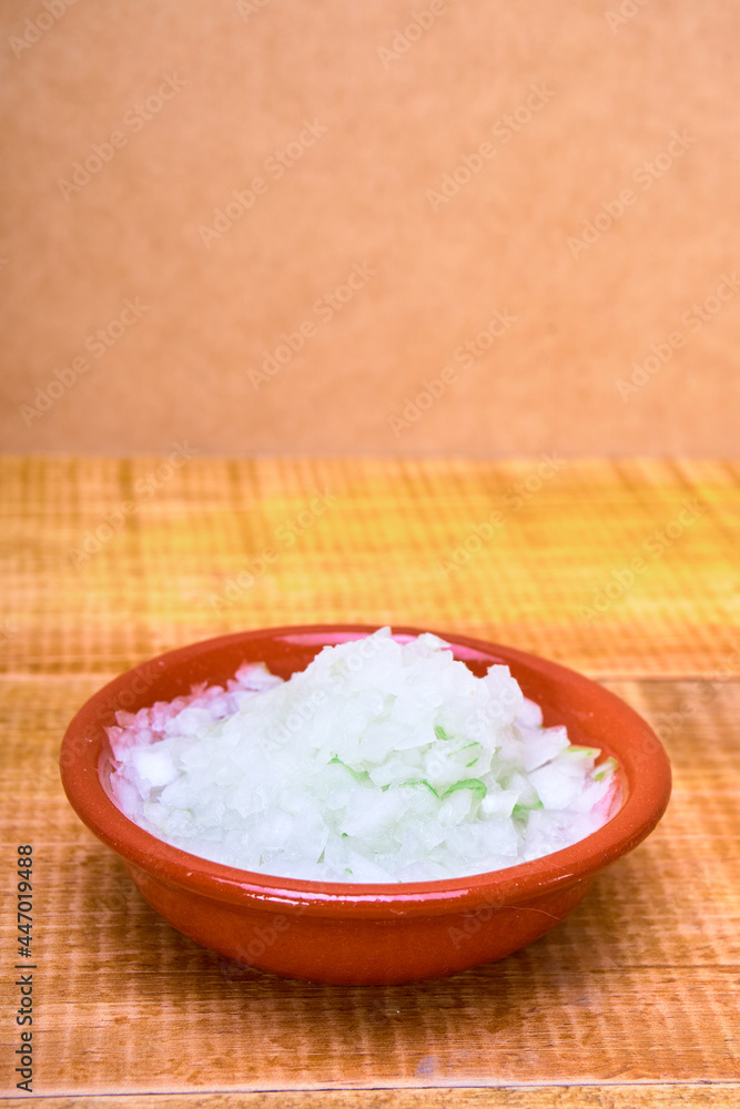 shredded onion on a earthenware plate on a wooden surface and wooden background. mexican food concept. copy space for advertising. shredded onion on a earthenware plate on a wooden surface and wooden background. mexican food concept. copy space for advertising.