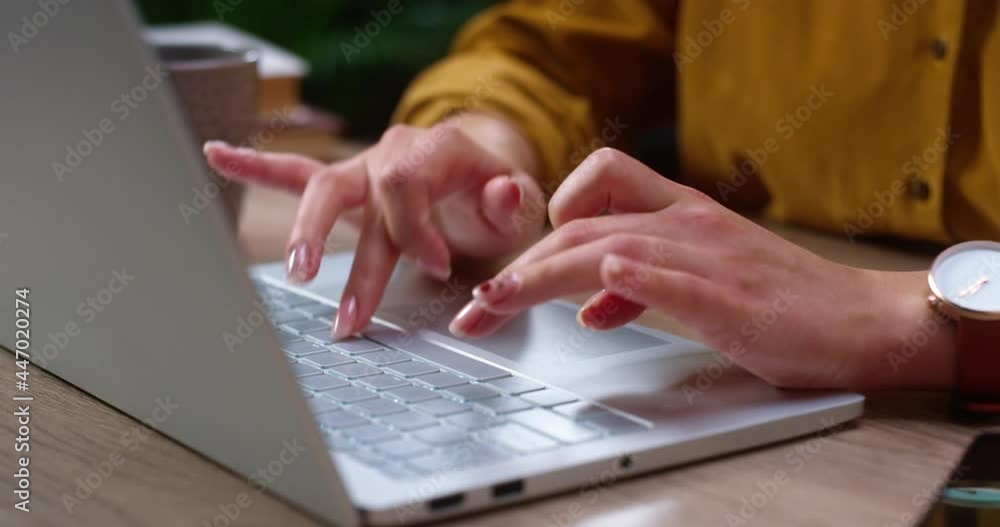 Millennial caucasian girl sitting at the table, looking at the laptop screen while having conversation. Young woman typing at the laptop keyboard at the office Millennial caucasian girl sitting at the table, looking at the laptop screen while having conversation. Young woman typing at the laptop keyboard at the office