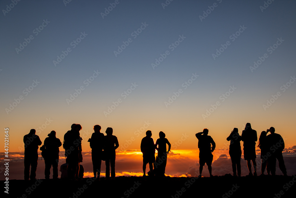 People watching the sunset above the clouds at Haleakalā in Maui, Hawaii.