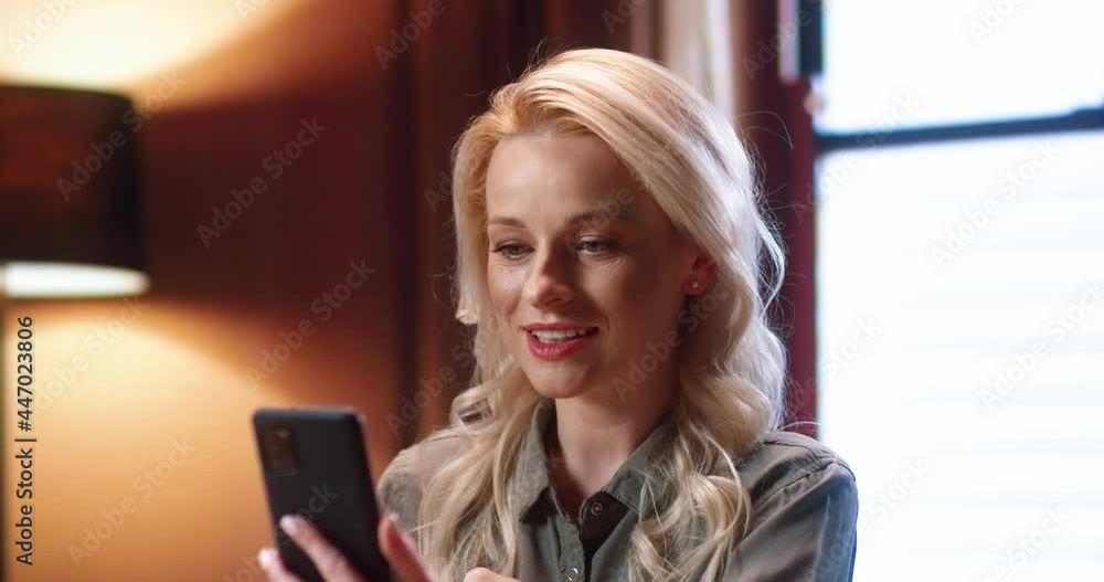 Pleasure chat. Portrait of blonde young woman looking at phone screen while having online conversation. Amazed overjoyed millennial woman talking with happy smile. Chat with clients concept Pleasure chat. Portrait of blonde young woman looking at phone screen while having online conversation. Amazed overjoyed millennial woman talking with happy smile. Chat with clients concept