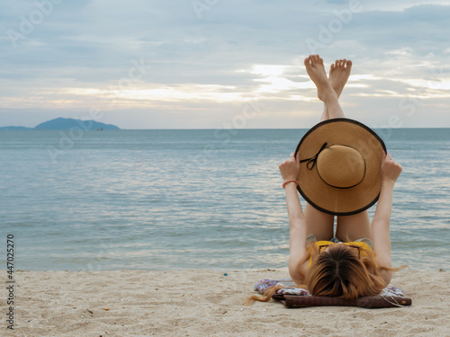 woman laying down and lifting her legs up to sky on the beach