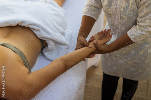 Profissional fazendo massagem relaxante no braço da cliente photo