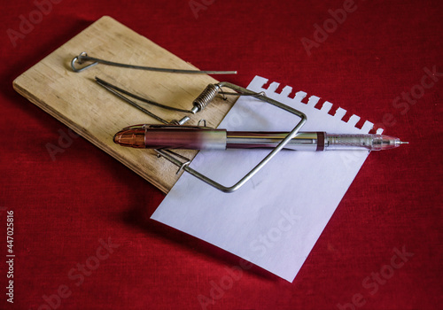 A fountain pen on a mousetrap on a sheet of writing paper for notes.